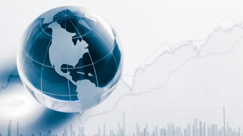 Business concept. Glass globe (america map) and stock market chart on newspaper background