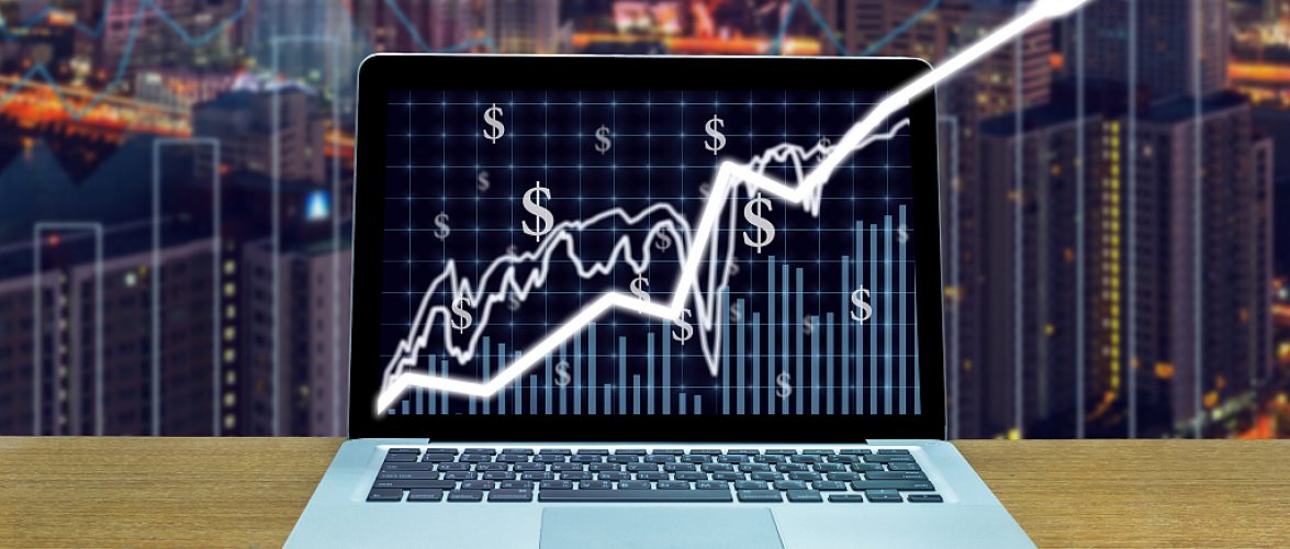 Stock exchange market trading graph over the screen of computer laptop on wood table over the photo blurred of trading graph background, business marketing trade concept