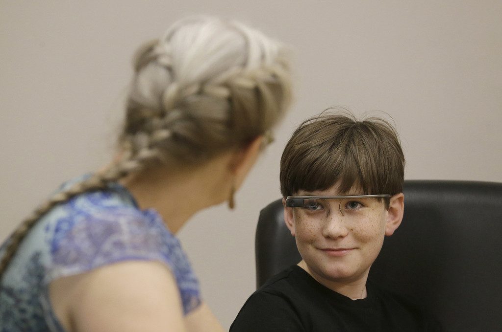 Julian Brown, right, talks with his mother Kristen during a meeting with Jena Daniels, a clinical research coordinator at The Wall Lab in Stanford, Calif., Wednesday, June 22, 2016. Like many autistic children, Brown, 10, has trouble reading emotions in people's faces, one of the biggest challenges for people with the neurological disorder. Now Brown is getting help from "autism glass" - an experimental device that records and analyzes faces in real time and alerts him to the emotions they're expressing. (AP Photo/Jeff Chiu)