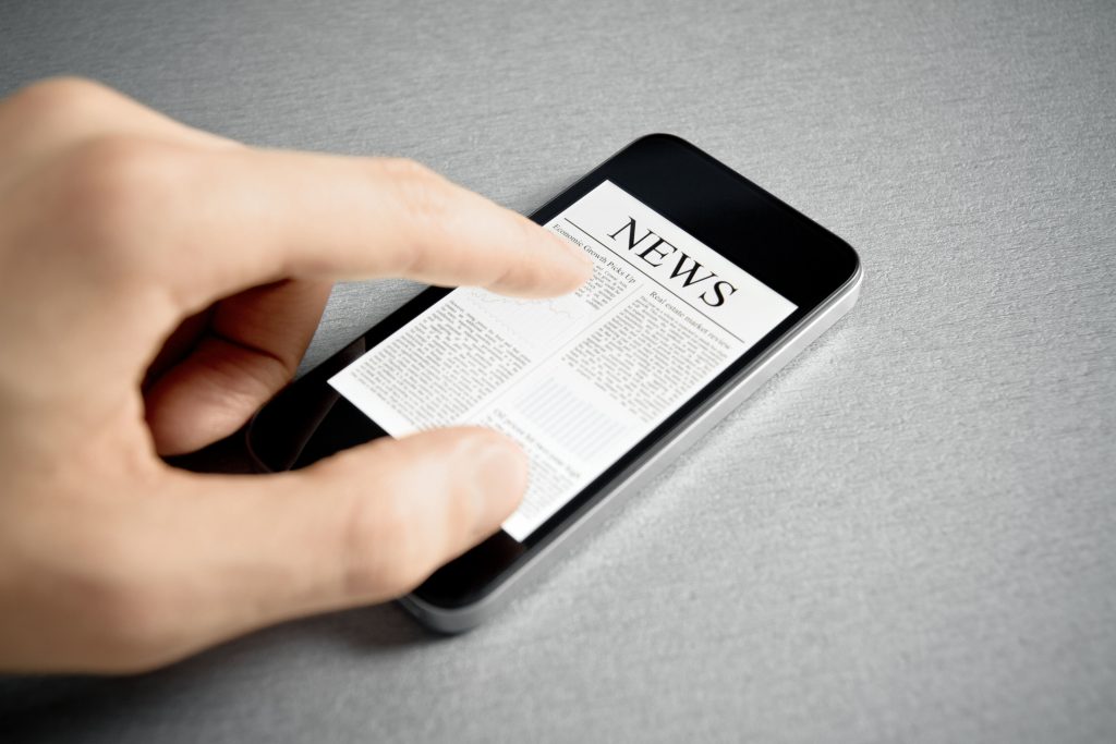 Man hand touch screen with news on contemporary mobile phone. Added a slight vignetting for dramatic effect and focus on the main headline.