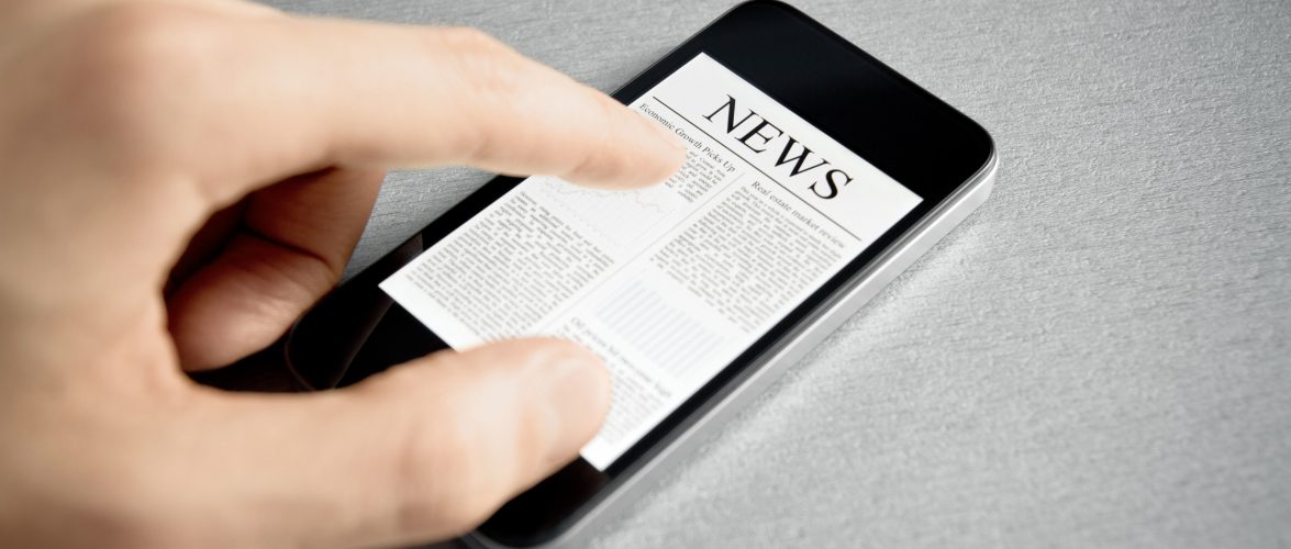 Man hand touch screen with news on contemporary mobile phone. Added a slight vignetting for dramatic effect and focus on the main headline.