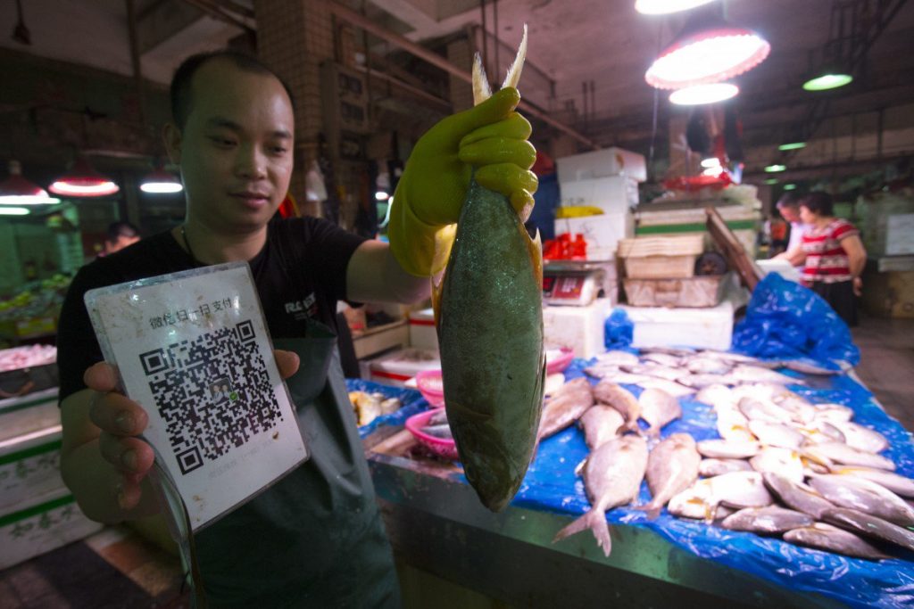 Fish Vendor Wu Weibin at a wet market in Shenzhen, China, takes mobile payment. Photo: SCMP
