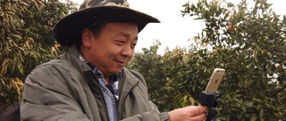 Zhong Haihui, a fruit farmer from central China's Hunan province, uses an iPhone 6, a small tripod and a power bank when live-streaming video for short video app operator Kuaishou and e-commerce platform Taobao Marketplace. Photo: Chris Chang