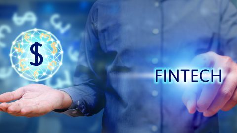 Financial technology concept, man pressing text fintech and holding global currency. Source: Tuchong.