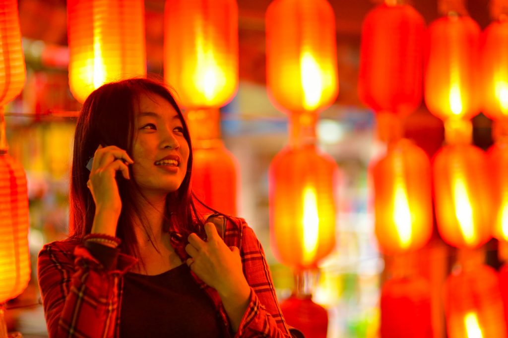 Chinese teenager with cell phone near Chinese lanterns. Source: Tuchong.