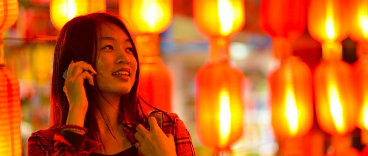 Chinese teenager with cell phone near Chinese lanterns. Source: Tuchong.