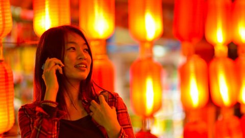 Chinese teenager with cell phone near Chinese lanterns. Source: Tuchong.