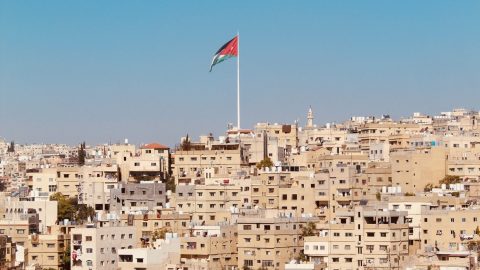 A Jordanian flag flutters above the cityscape. Photo by Who’s Denilo? on Unsplash.