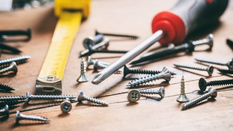 Screwdriver, nails and meter on wooden background. Photo : Tuchong