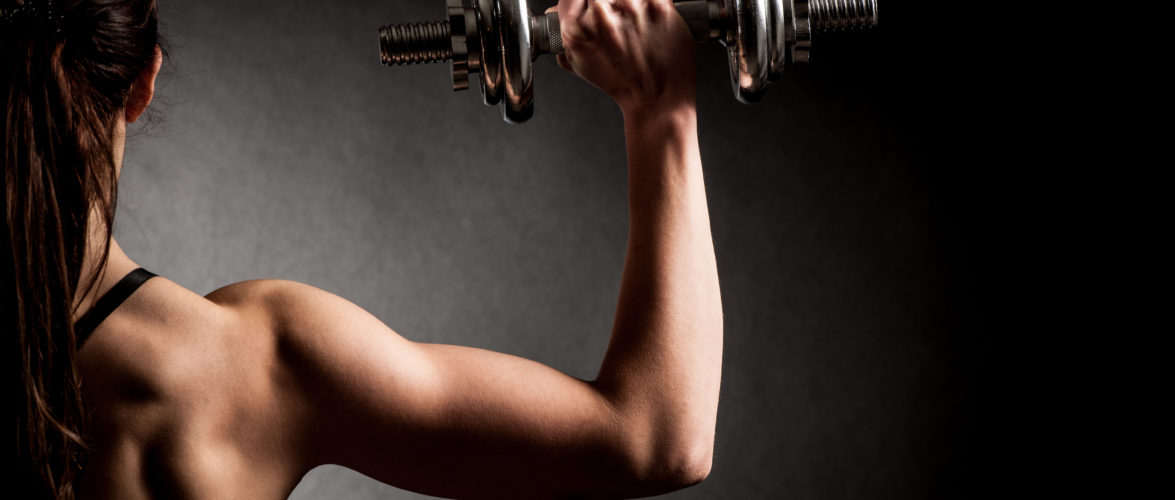 Atractive fit woman works out with dumbbells as a fitness conceptual over dark background. [Photo: Tuchong]