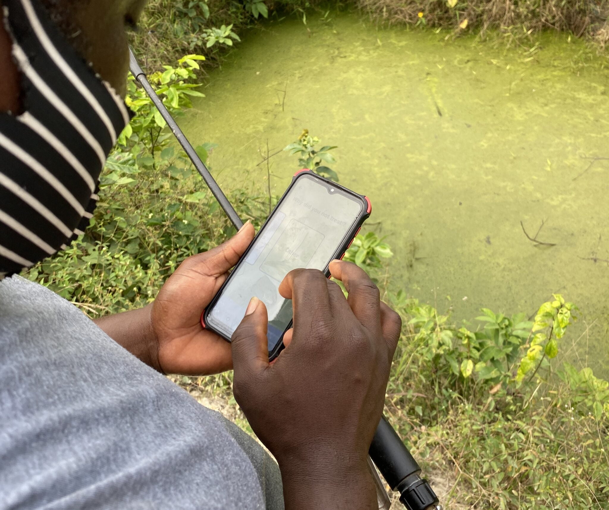 A field worker uses ZzappMalaria to scan bodies of water set for treatment. Photo courtesy of ZzappMalaria via NoCamels.