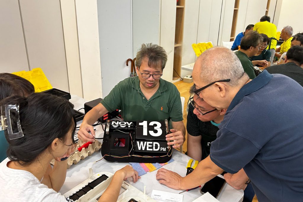 A volunteer at Repair Kopitiam inspecting a clock brought in for repair.