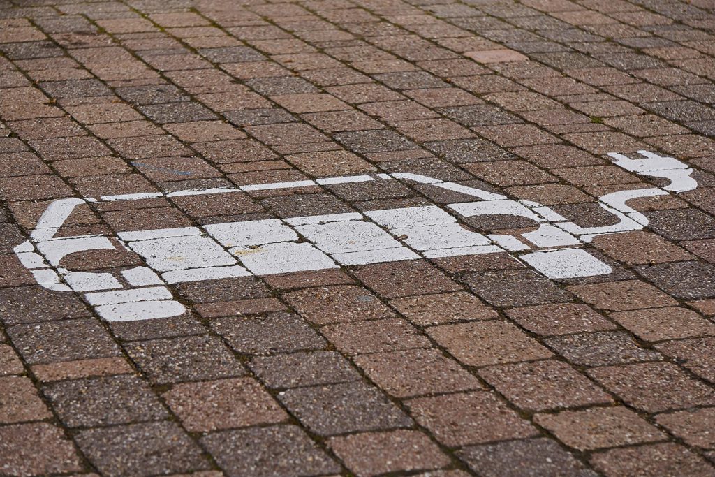 A sign painted on the pavement indicates an EV recharging station.