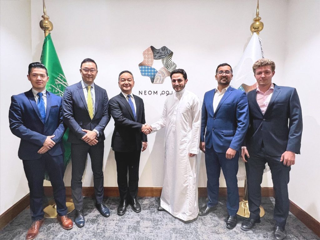 Photo of James Peng (third from left), co-founder and CEO of Pony.ai, shaking hands with Majid Mufti (third from right), CEO of Neom Investment Fund, alongside representatives from both organizations.