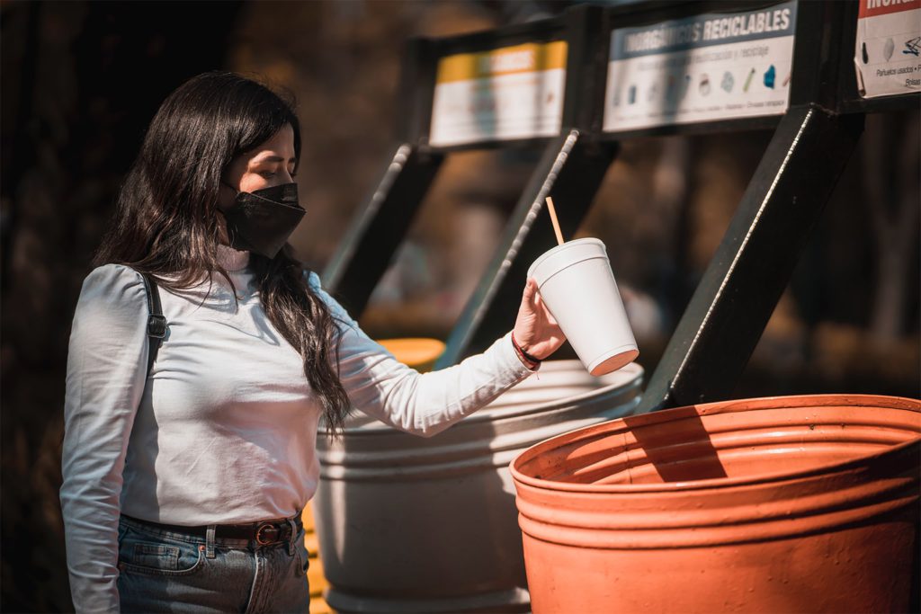 Photo of a woman throwing out a styrofoam cup in Mexico City.
