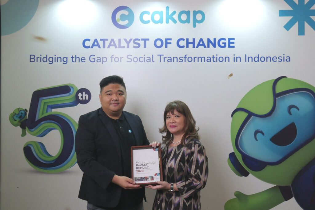 Photo of Tomy Yunus, co-founder and CEO of Cakap, presenting Shinta Kamdani, chairwoman of the Indonesian Employers Association (APINDO), with a copy of its latest impact report.
