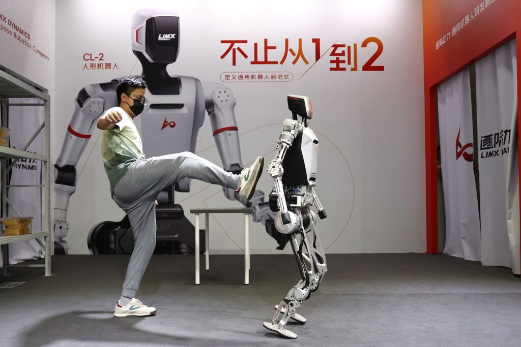 Photo of a LimX Dynamics staff member of LimX Dynamics booting the CL-1 humanoid robot during a live demo, highlighting its anti-inference capabilities.