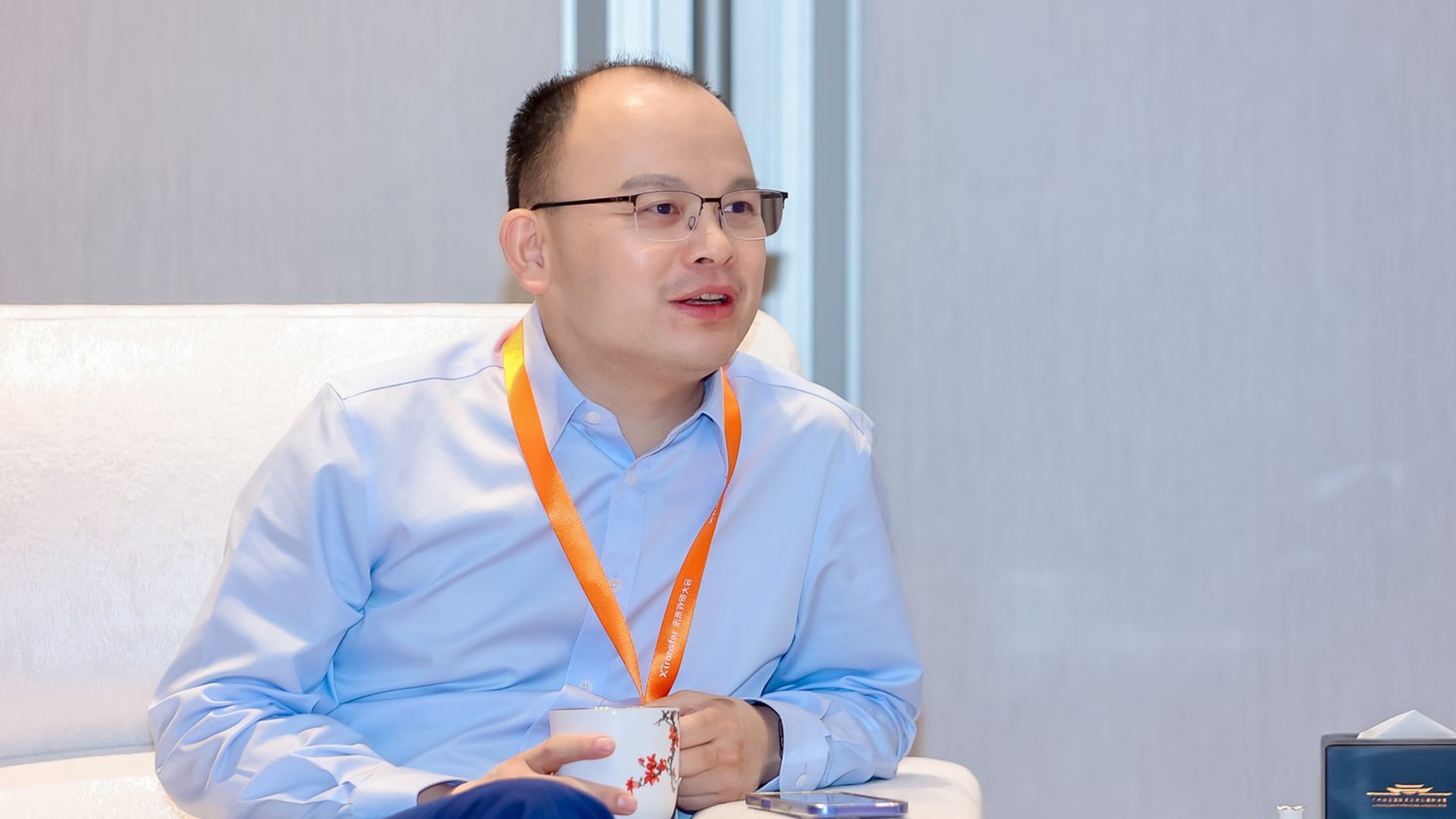 Photo of XTransfer founder Bill Deng speaking with members of the media during an interview session.