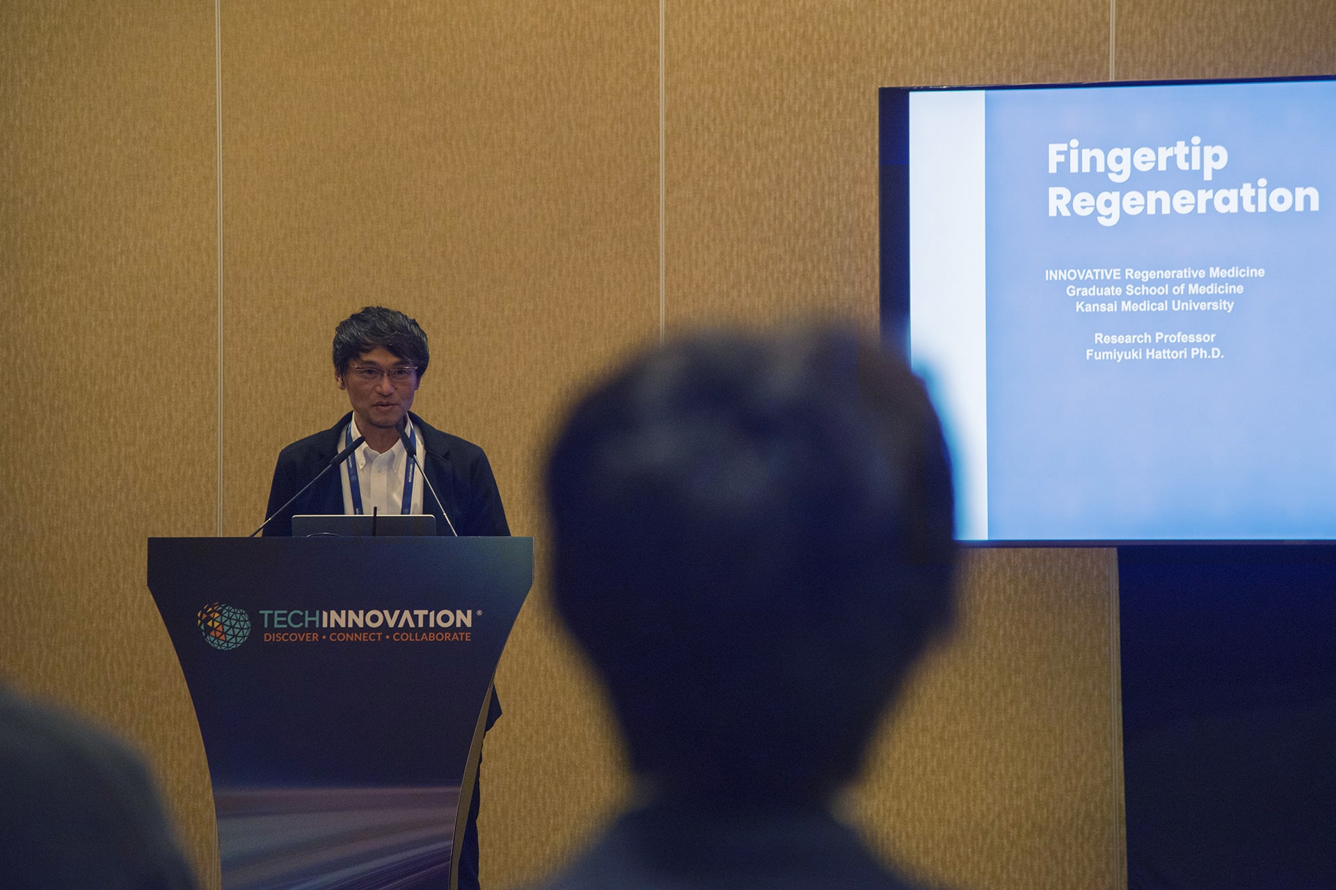 Photo of Fumiyuki Hattori from Kansai Medical University, speaking during the event about potential therapeutics using nail stem cells to regenerate fingertips lost to burns, accidents, or amputations.