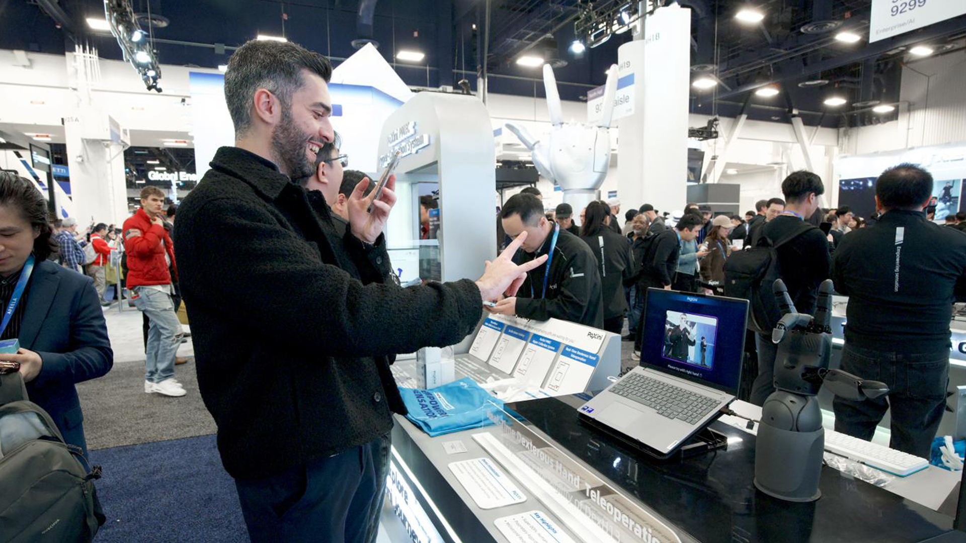 Photo shows CES 2026 attendees experiencing PaXini’s real-time dexterous hand teleoperation.