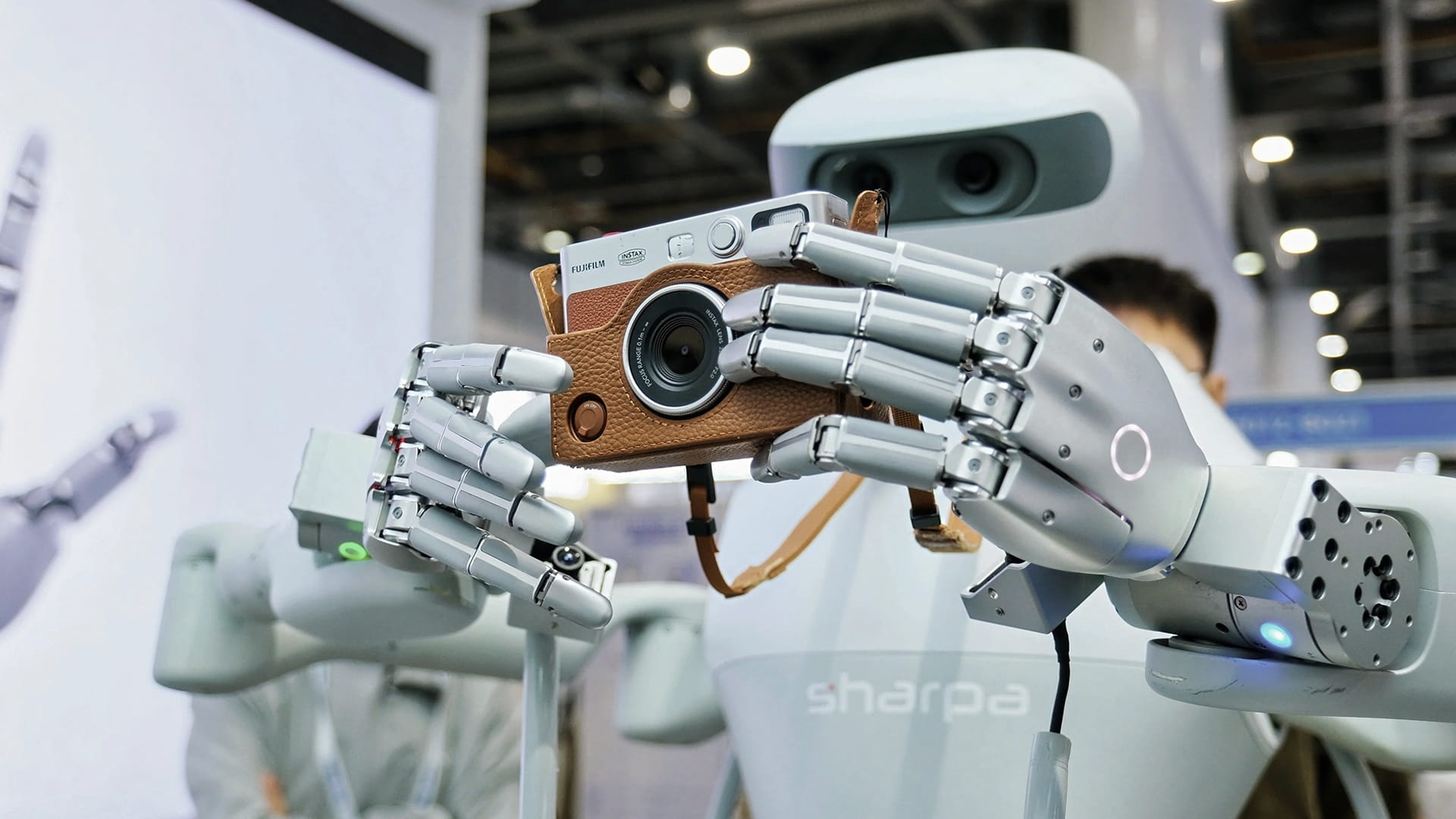 Photo shows the Sharpa North humanoid robot using its SharpaWave dexterous hand to hold a camera.