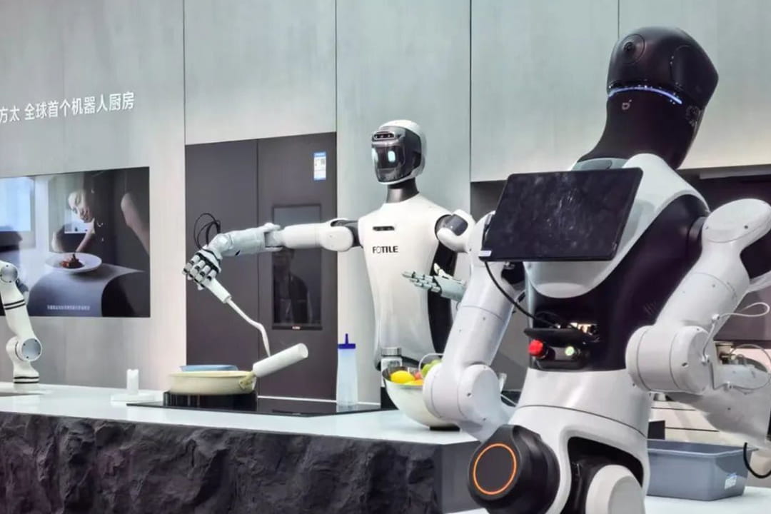 Photo shows the kitchen system set up by Fotile at AWE 2026, featuring humanoid robots designed to handle various tasks.