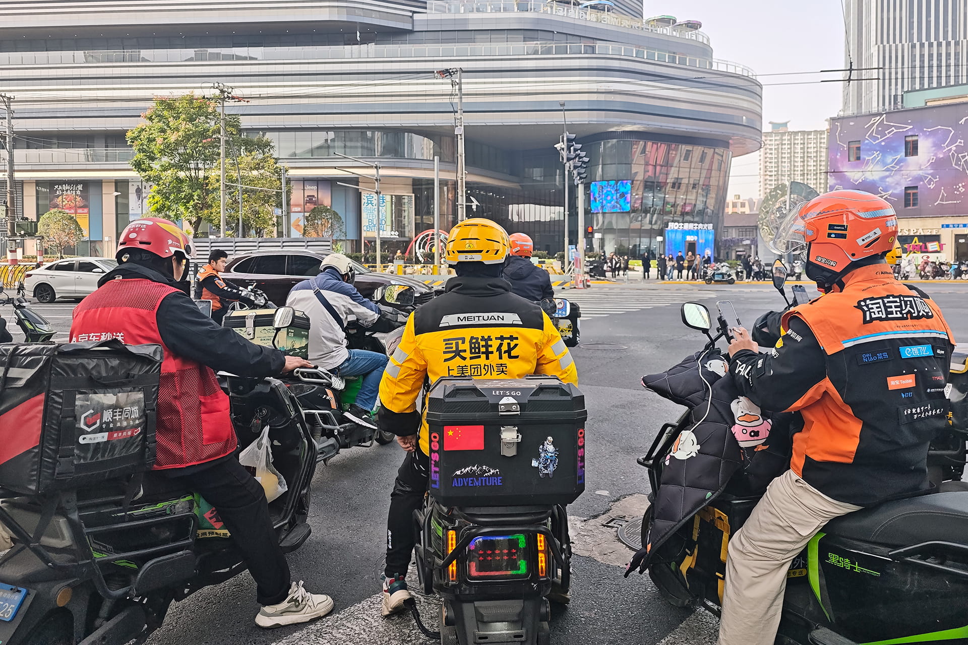 Photo shows delivery riders from multiple platforms cluster at an intersection in a Chinese city.