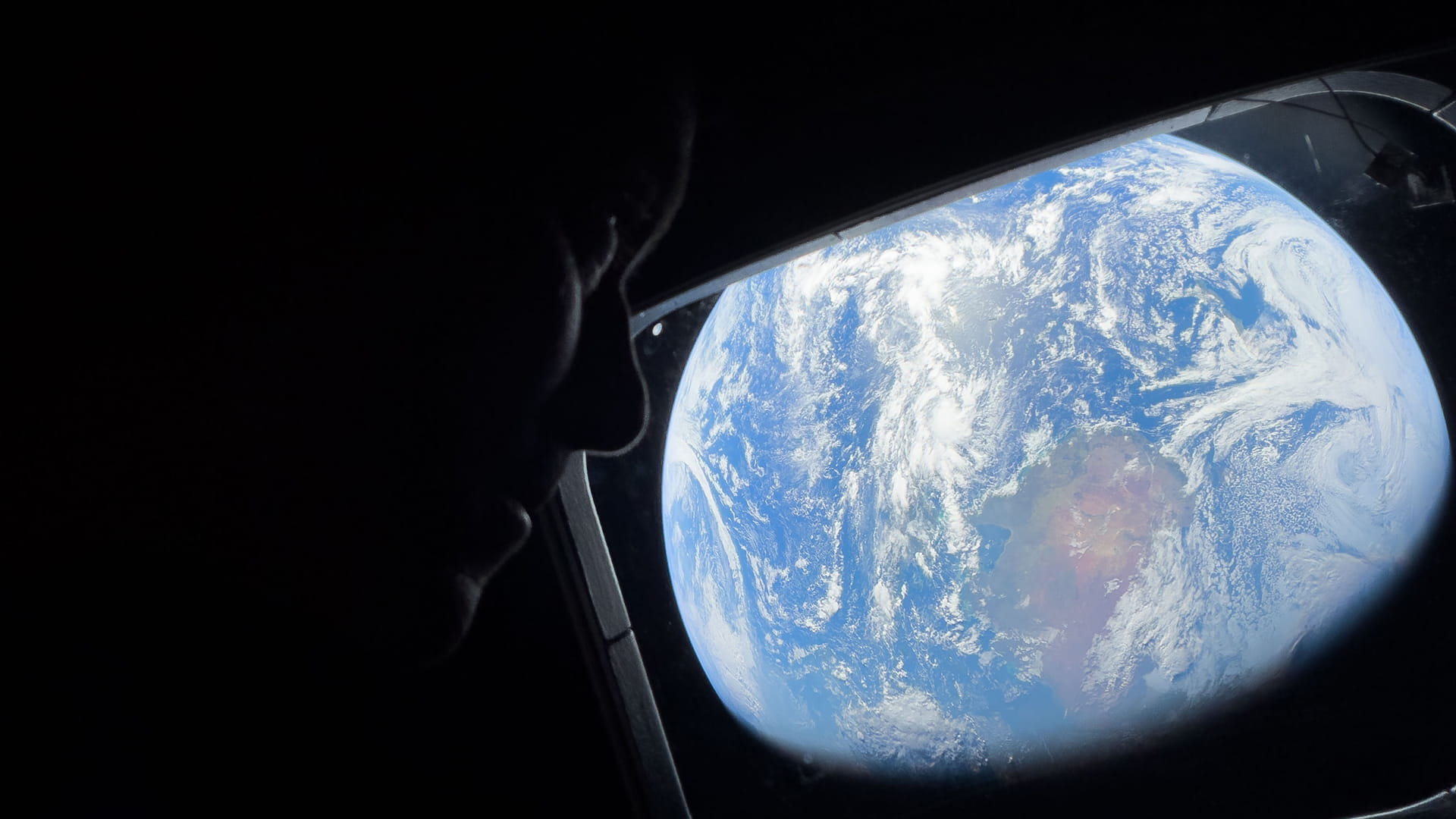 Photo shows NASA astronaut and Artemis 2 commander Reid Wiseman peering out of a window on the Orion spacecraft, looking back at Earth as the crew travels toward the moon on April 4.